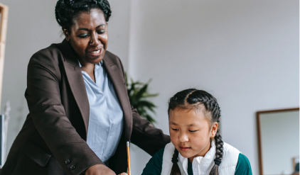 A teacher points out something to a student on her work.