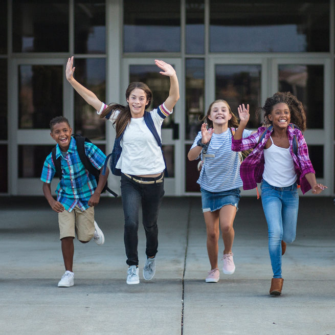 Four students run out of the school building happily