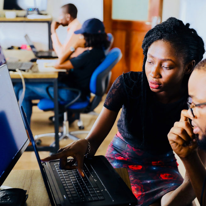 A teacher explains something on a computer monitor to her student.