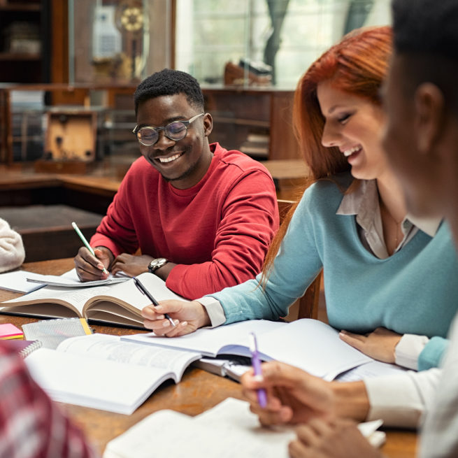 Students sit around a study room table laughing